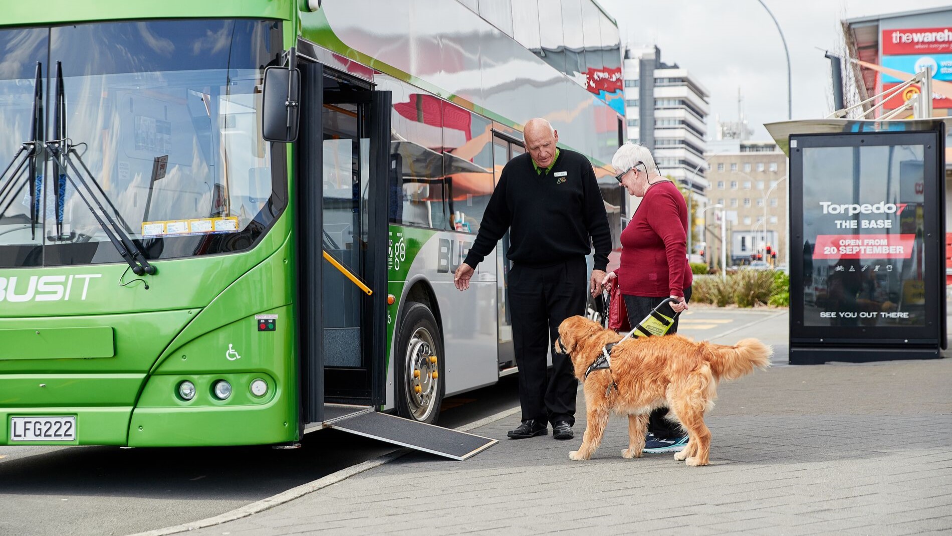 Bus driver helping a patron with an assistance dog board a BUSIT bus