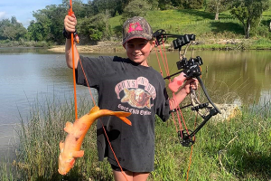 Mackenzie Pickering with bow and a captured koi