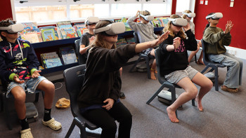 A group of students experience the virtual reality session in the school library.