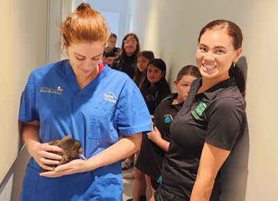 Image of a lady holding a kiwi and someone standing next to her