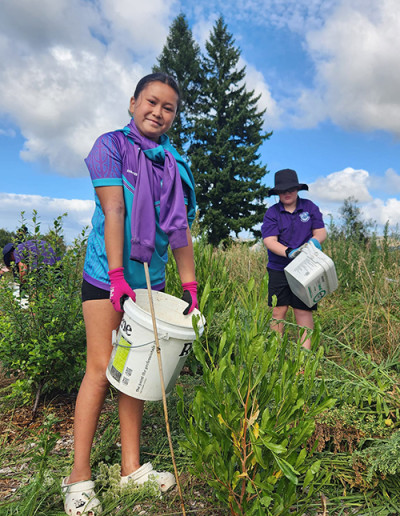 Image of a girl standing in a field holding a bucket