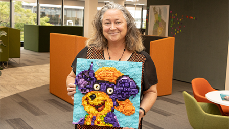 Image of a person holding a lego artwork of Ruben the road safety bear