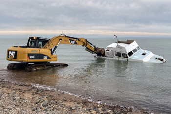 council contractors pull a 36-foot boat ashore at Waiomu for demolition and disposal