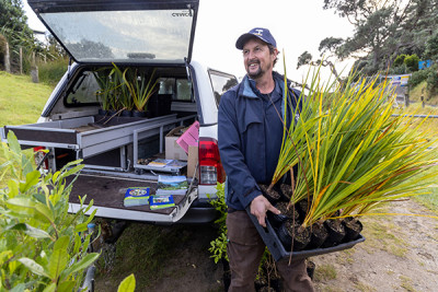 Community member holding a tray of plants ready for a Coastcare planting day