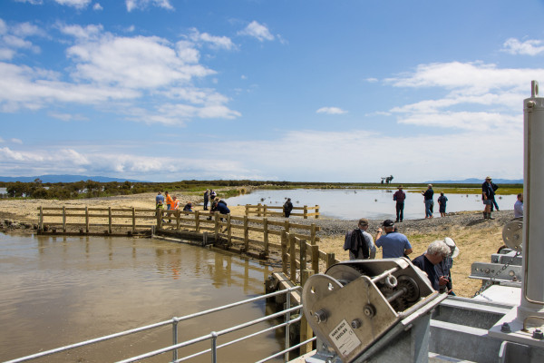 Stakeholders check out the newly completed project. This image shows the floodgate outlet (foreground) and habitat area (background).